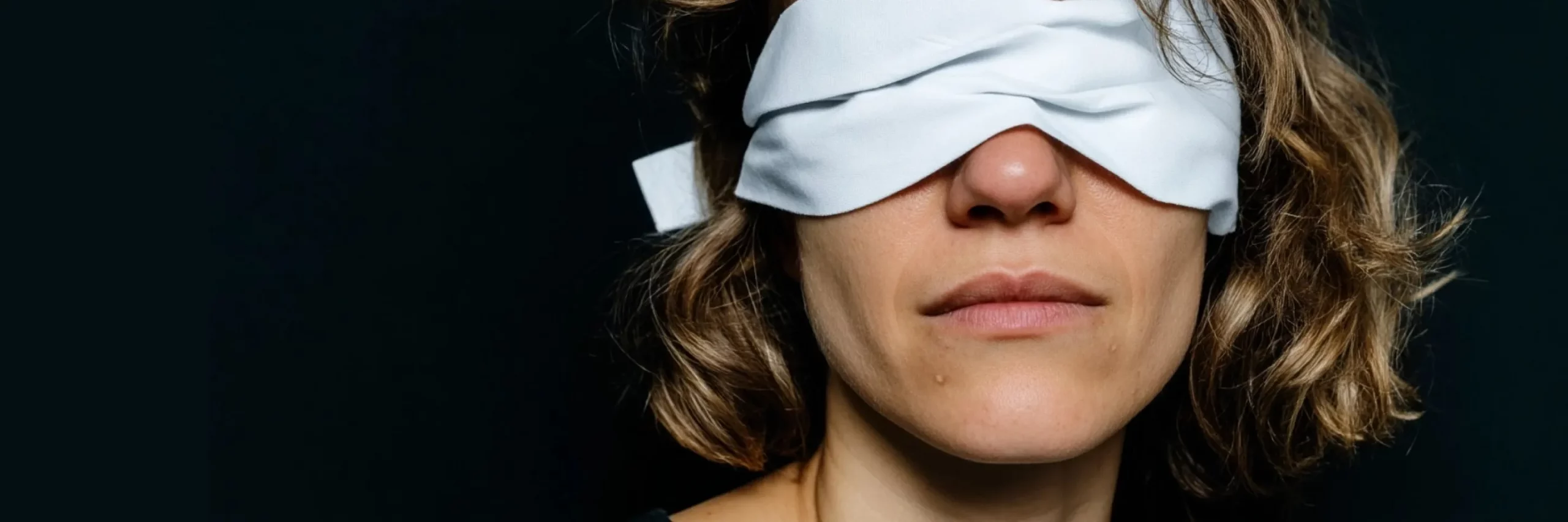 Eine Person mit verbundenen Augen und einem Lächeln im Gesicht.