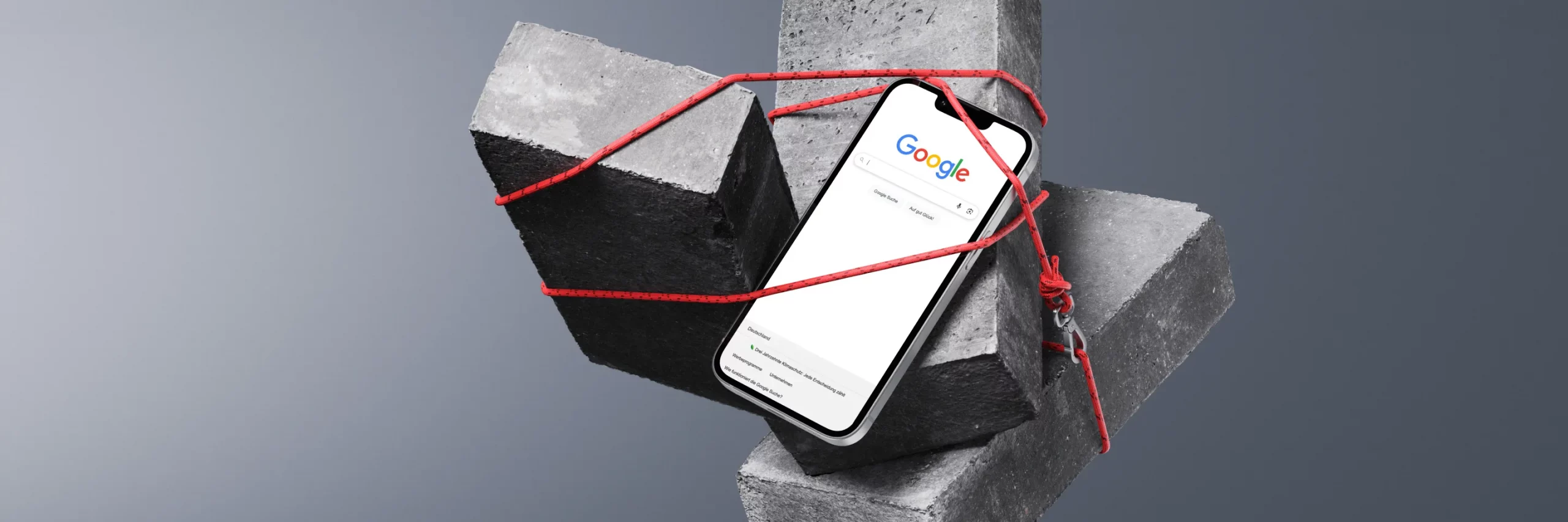 Ein Smartphone mit Google-Suche ist zwischen zwei Betonblöcken mit rotem Faden befestigt.