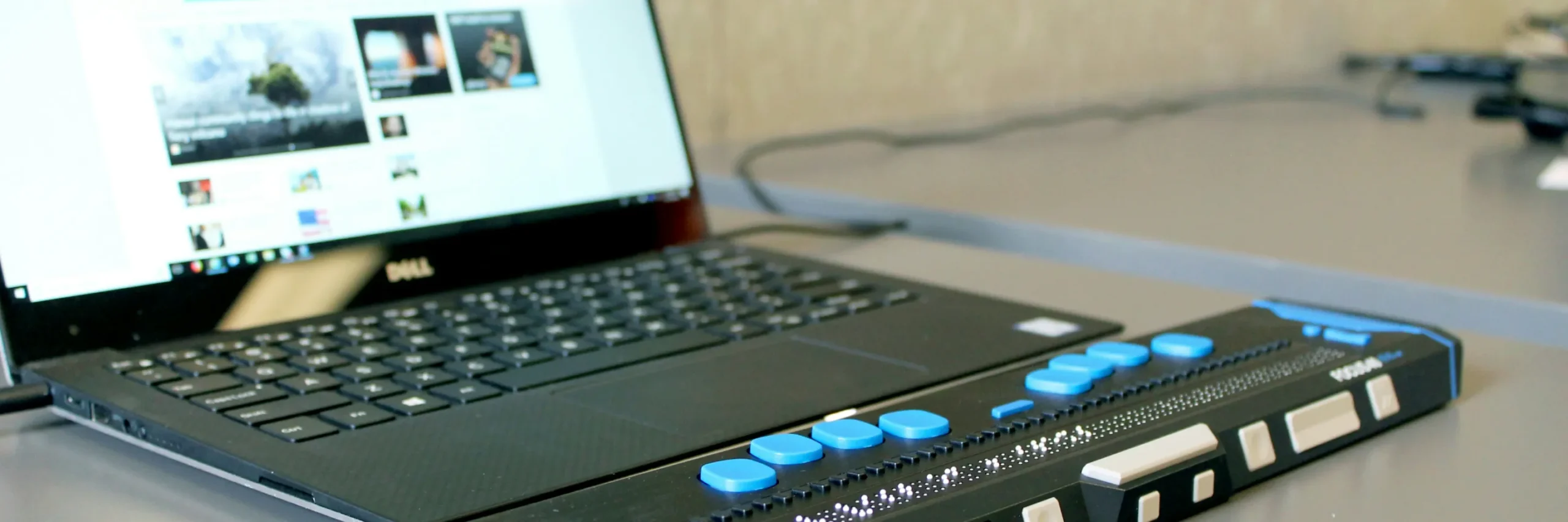 Ein Laptop mit Braille-Tastaturanschluss und angelegter Braillezeile.